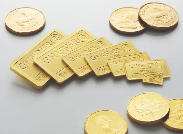 Funkelnde Goldbarren und Goldmünzen auf einem Weißen Tisch